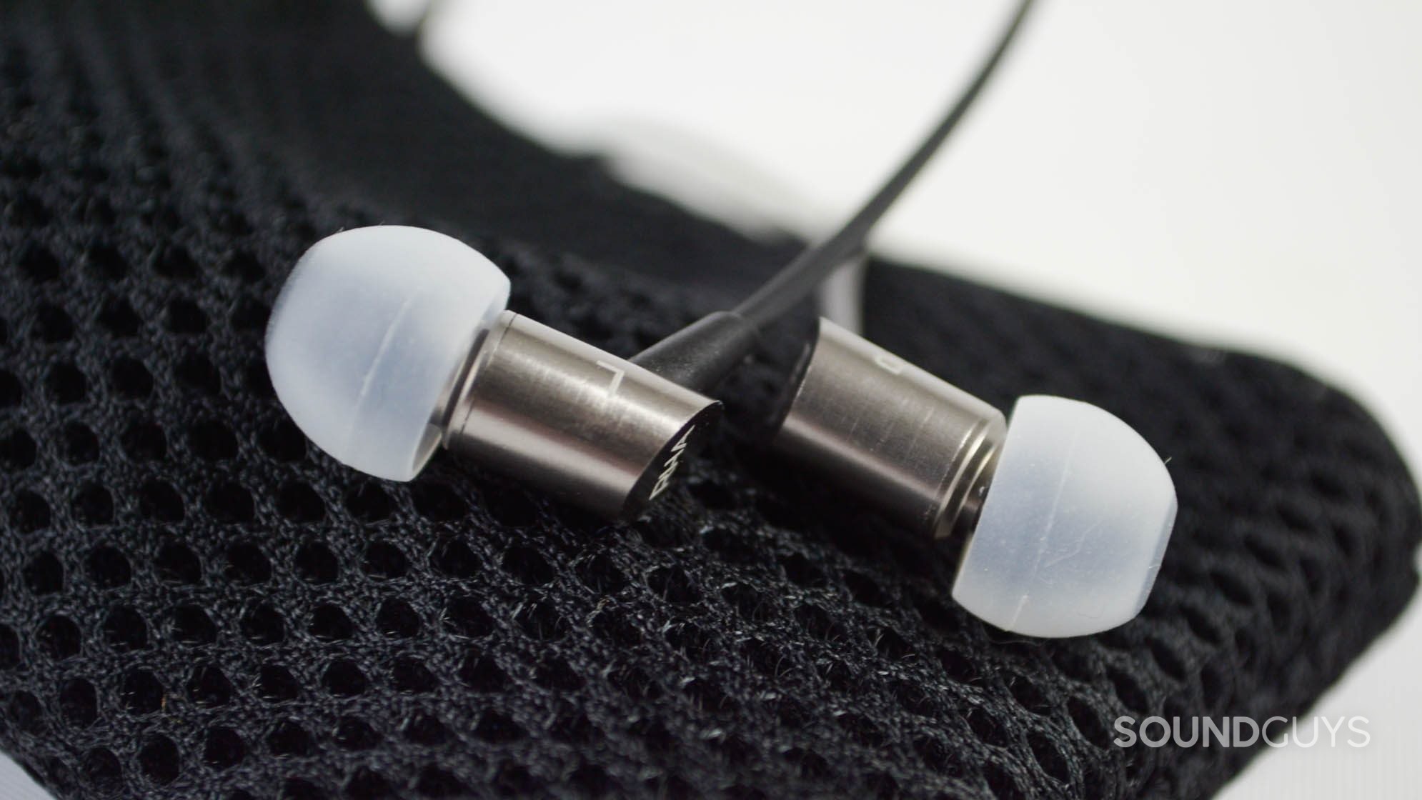 The RHA S500i earbuds on top of a mesh carrying pouch.