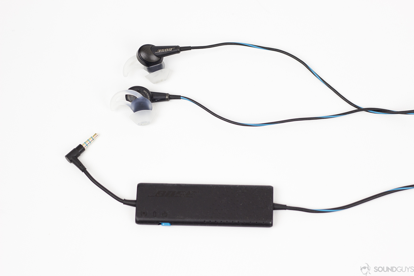 Bose QC 20 noise canceling earbuds and noise canceling controller on white background.