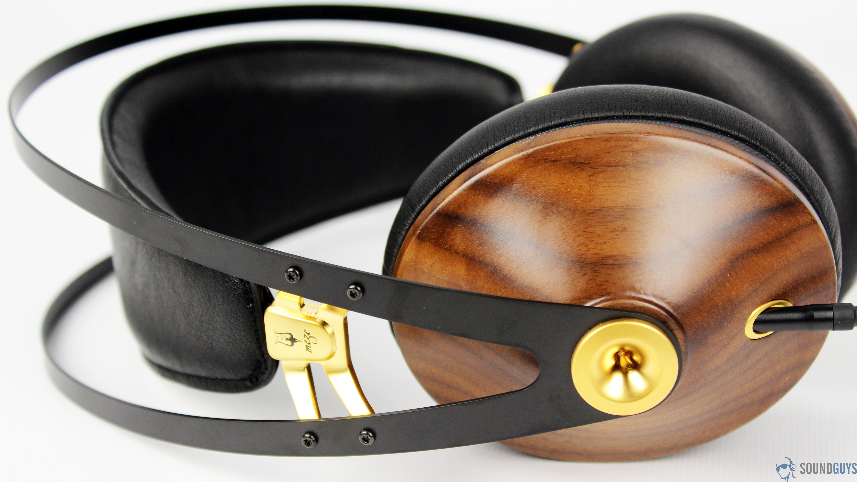 The Meze 99 Classics headphones lay flat against a white surface to show off the headband architecture.