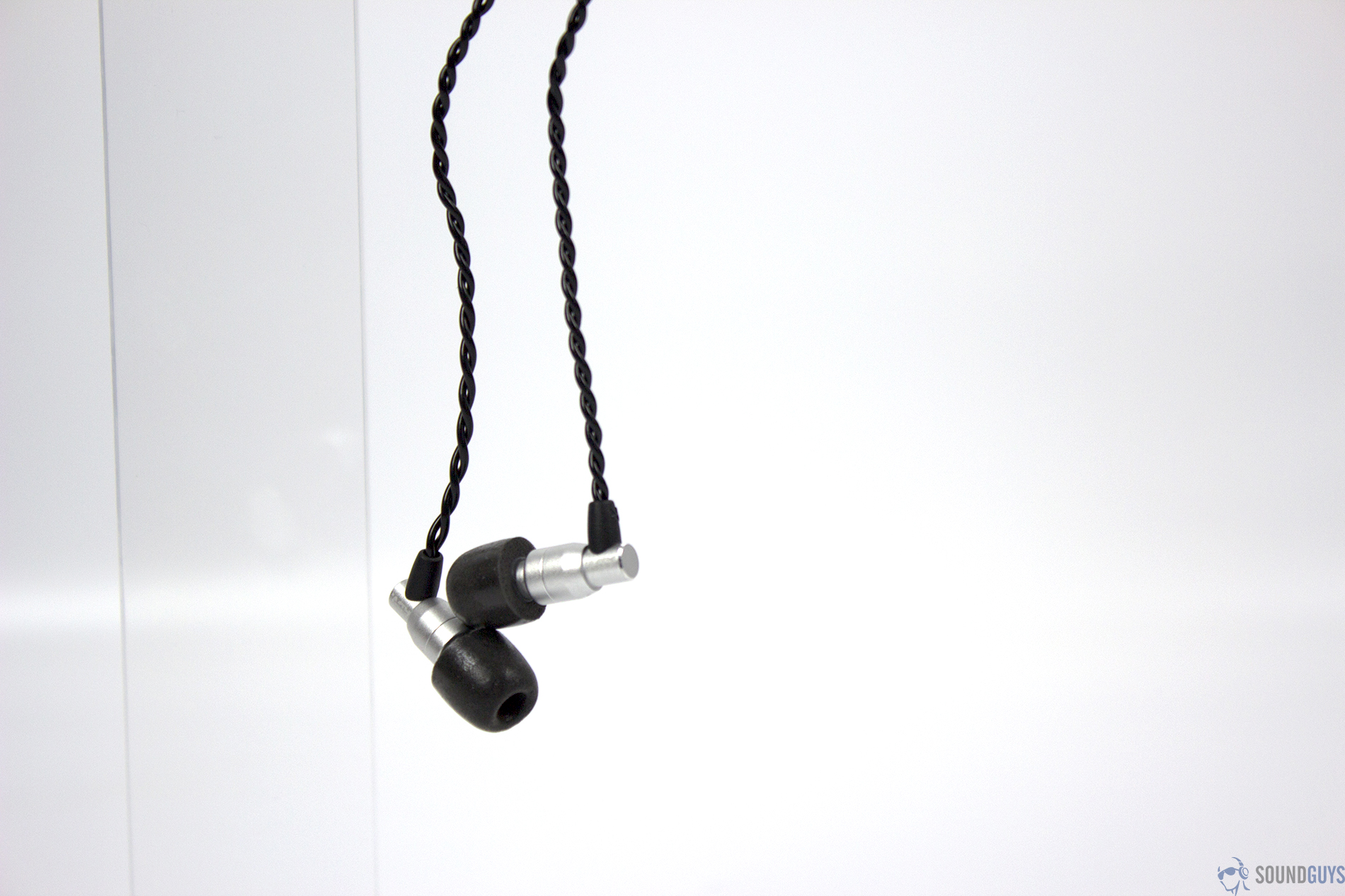 The ADV.SoundM4 earbuds hanging down vertically on the left third of the image.