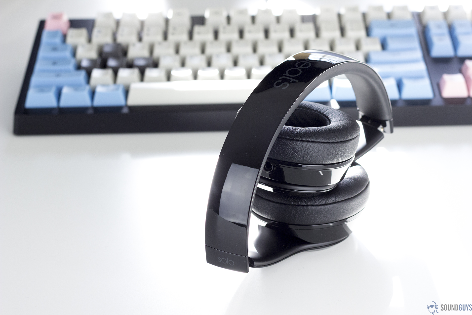 Pictured are the black Solo3 Wireless headphones on a white table in front of a keyboard. 