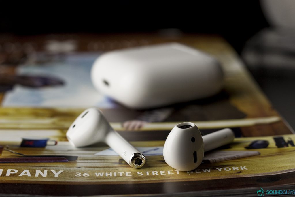 Apple AirPods: earbuds laying flat on a magazine with the case blurred out in the background
