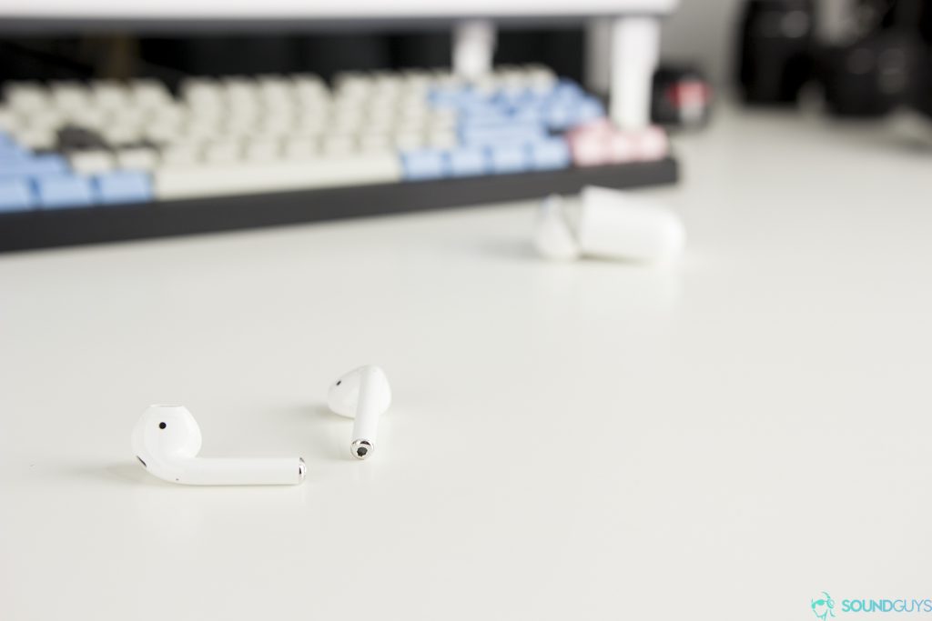 Apple AirPods: An image of the earbuds on a white table with a mechanical keybaord in the background.