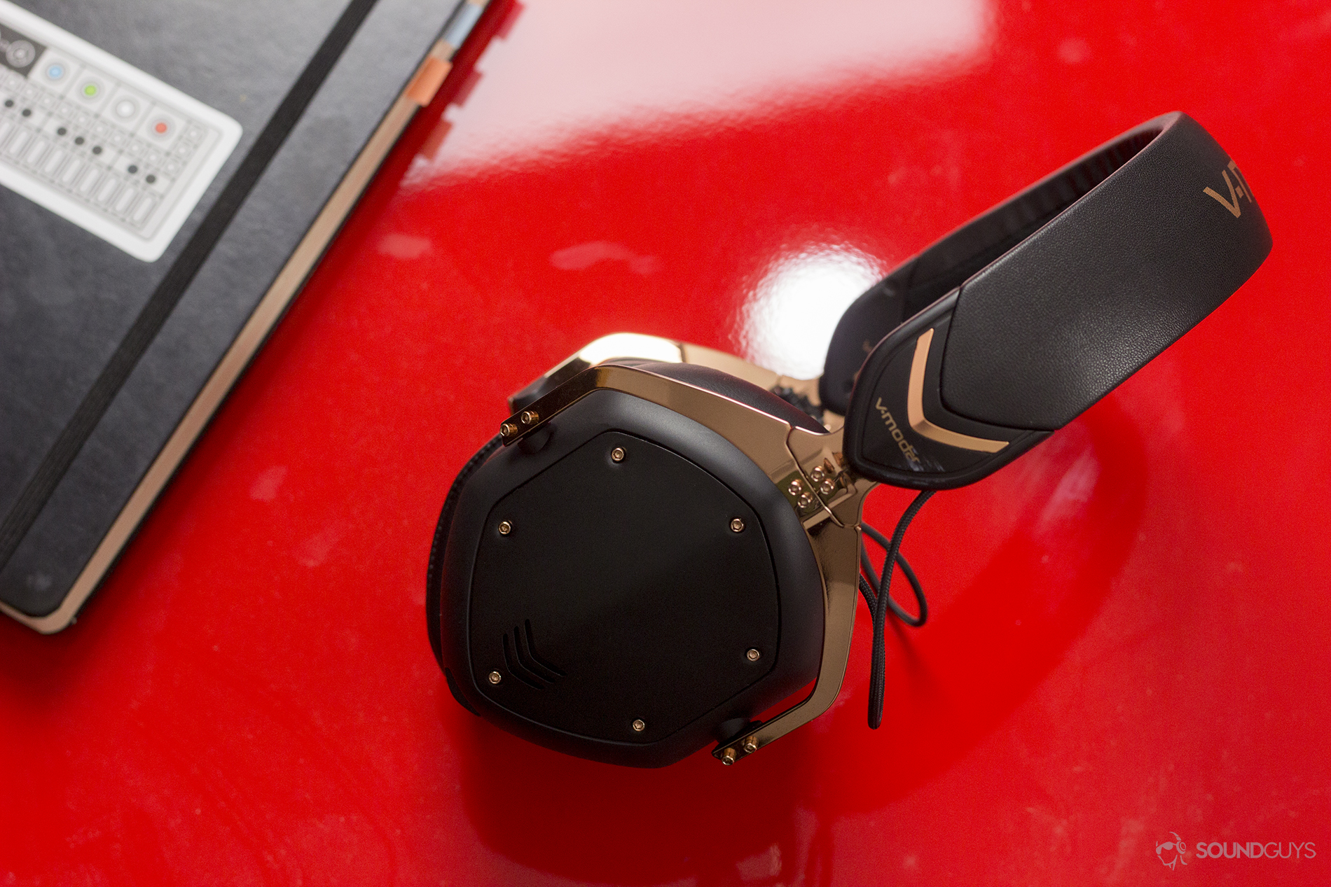 A top-down view of the headphones on a red surface with a notebook off to the side.