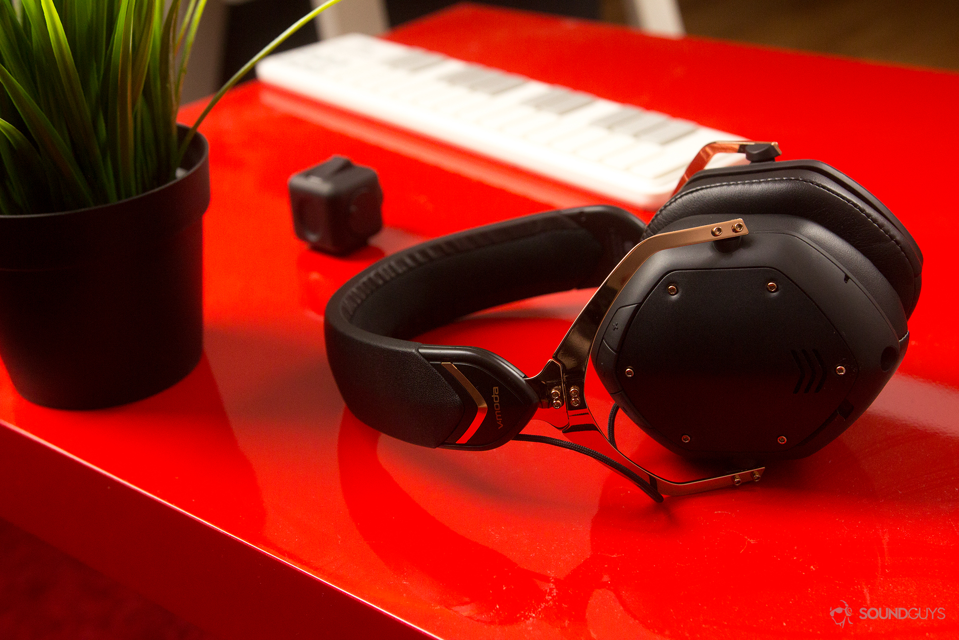 The headphones on a red table with a plant nearby.