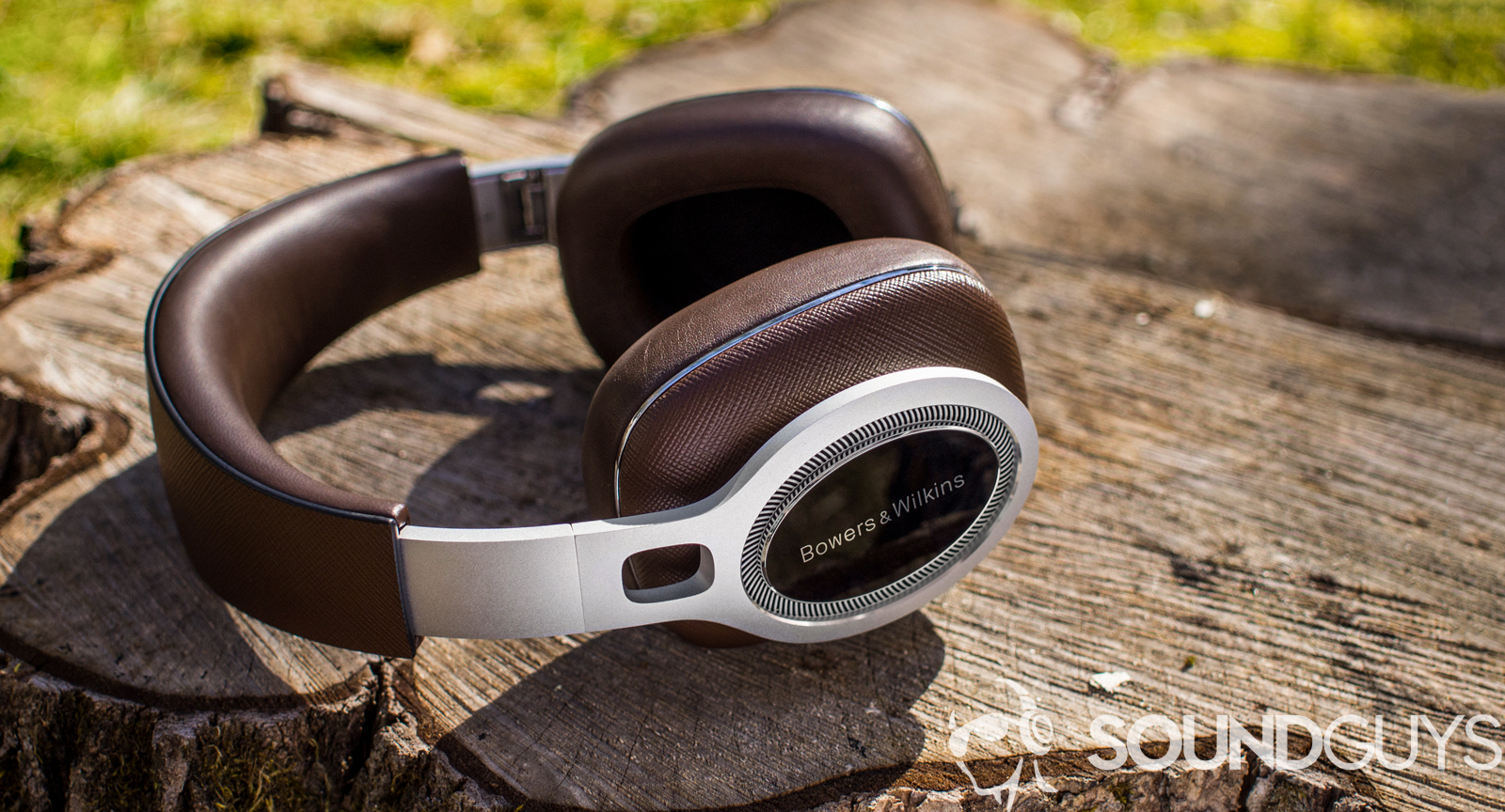 A photo of the Bowers and Wilkins P9 Signature headphones resting on a stump.