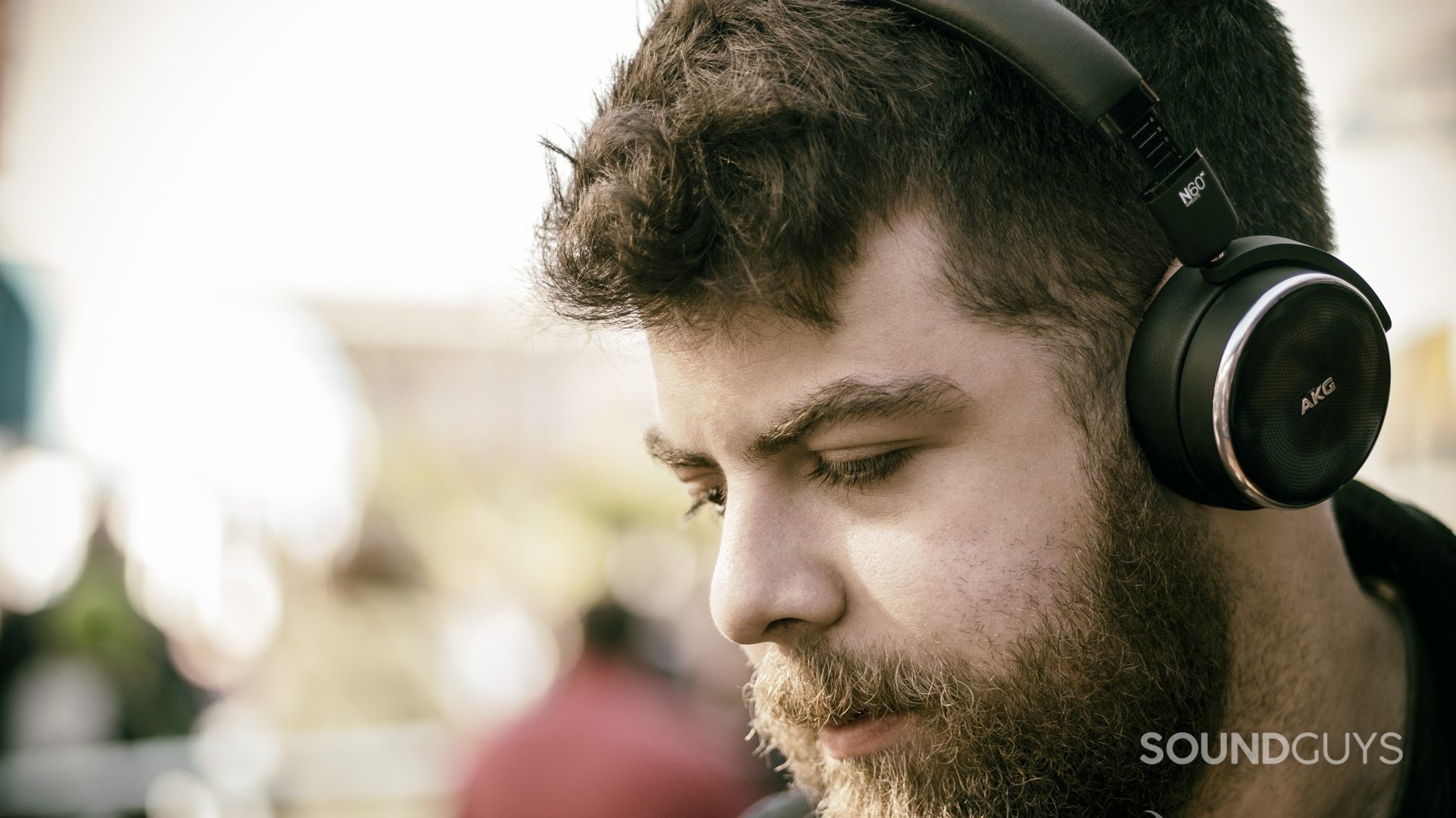 A man wears the AKG N60NC on-ear noise canceling headphones outside.