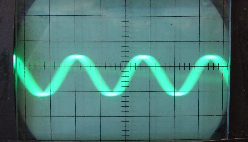 A photo of an oscilloscope readout with a sine wave.
