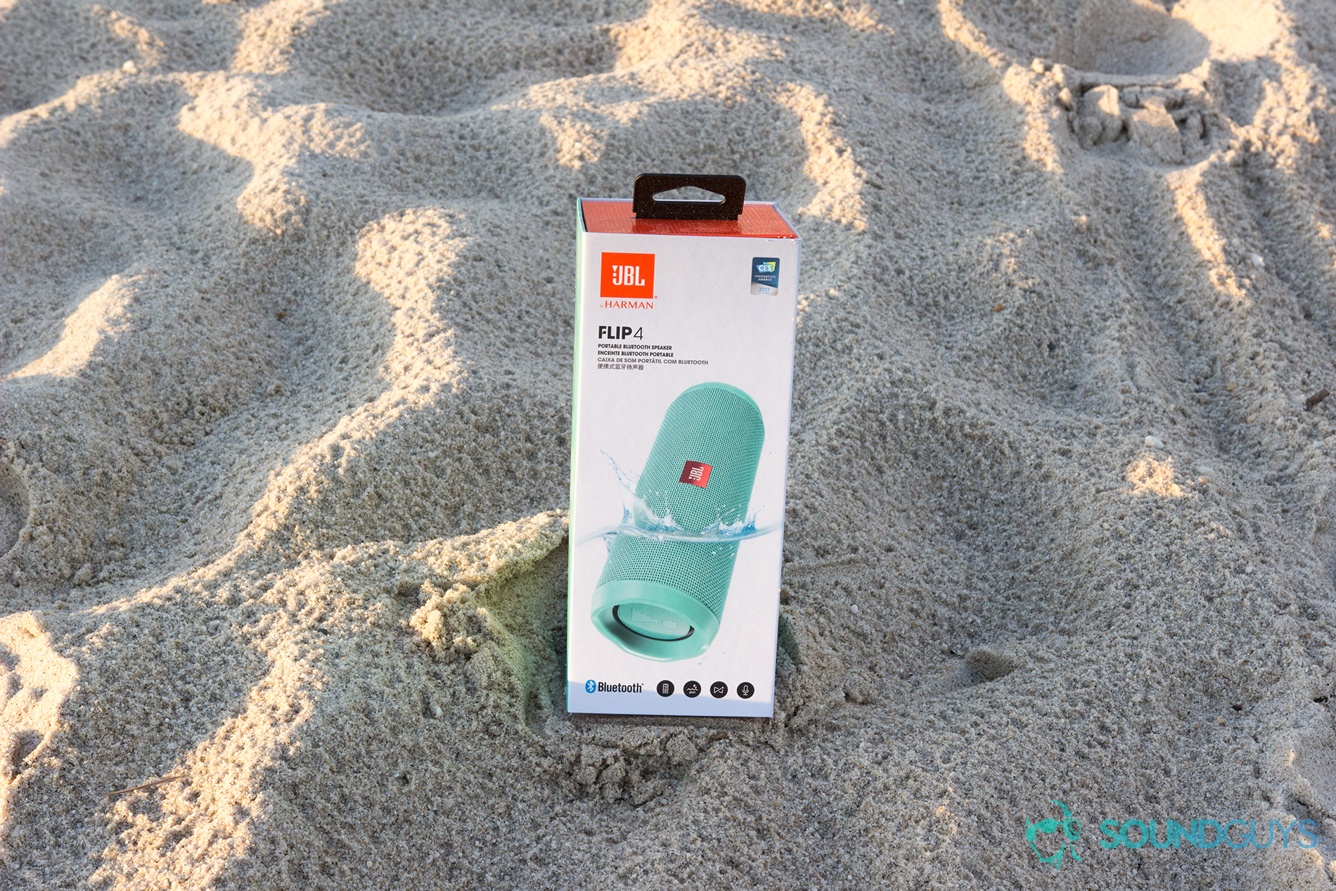 JBL Flip 4 retail packaging on sand. 