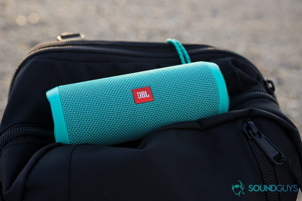 The teal JBL Flip 4 pictured on top of a black backpack.