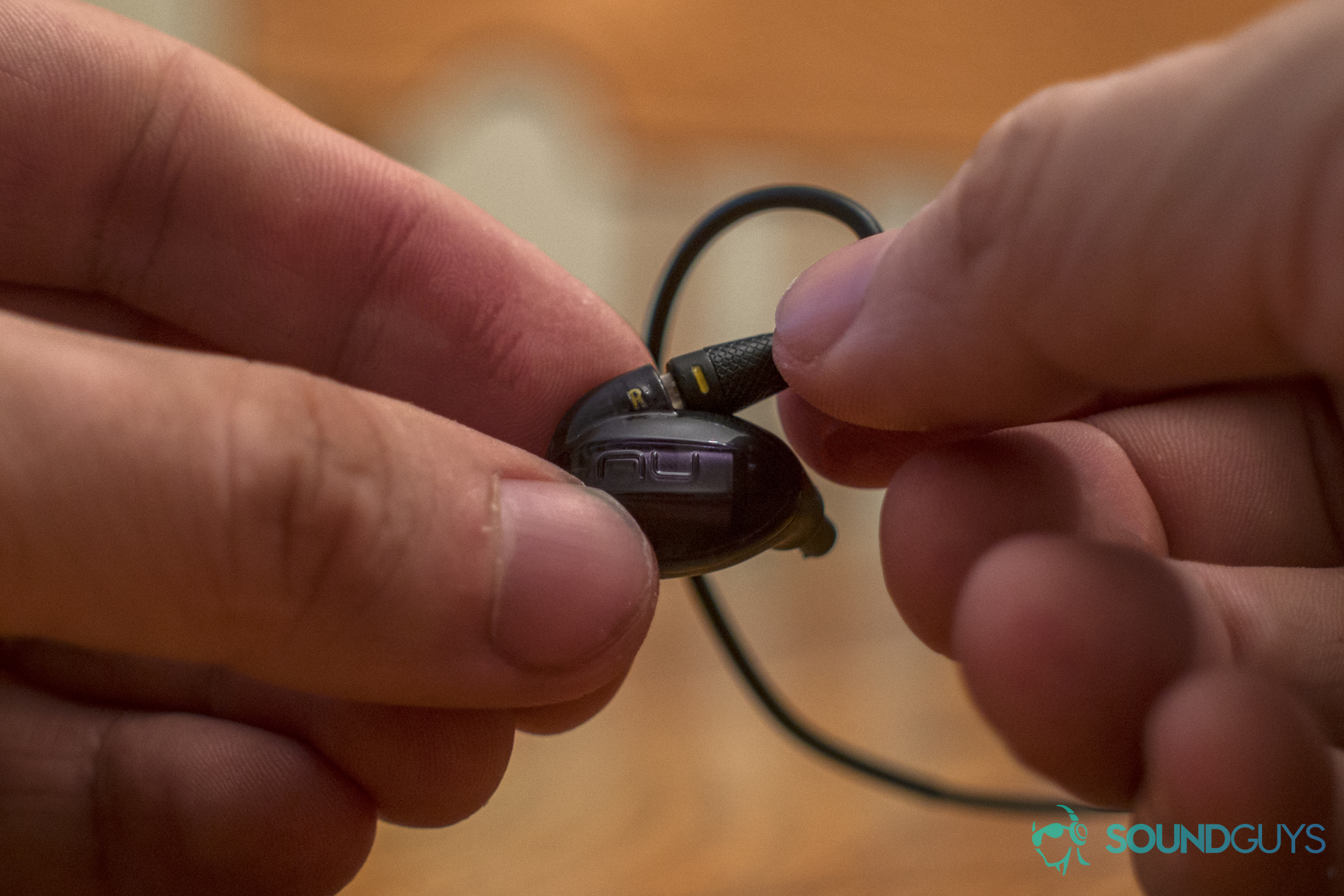 A photo demonstrating the NuForce x Massdrop EDC In-ear monitor with its cables being removed.