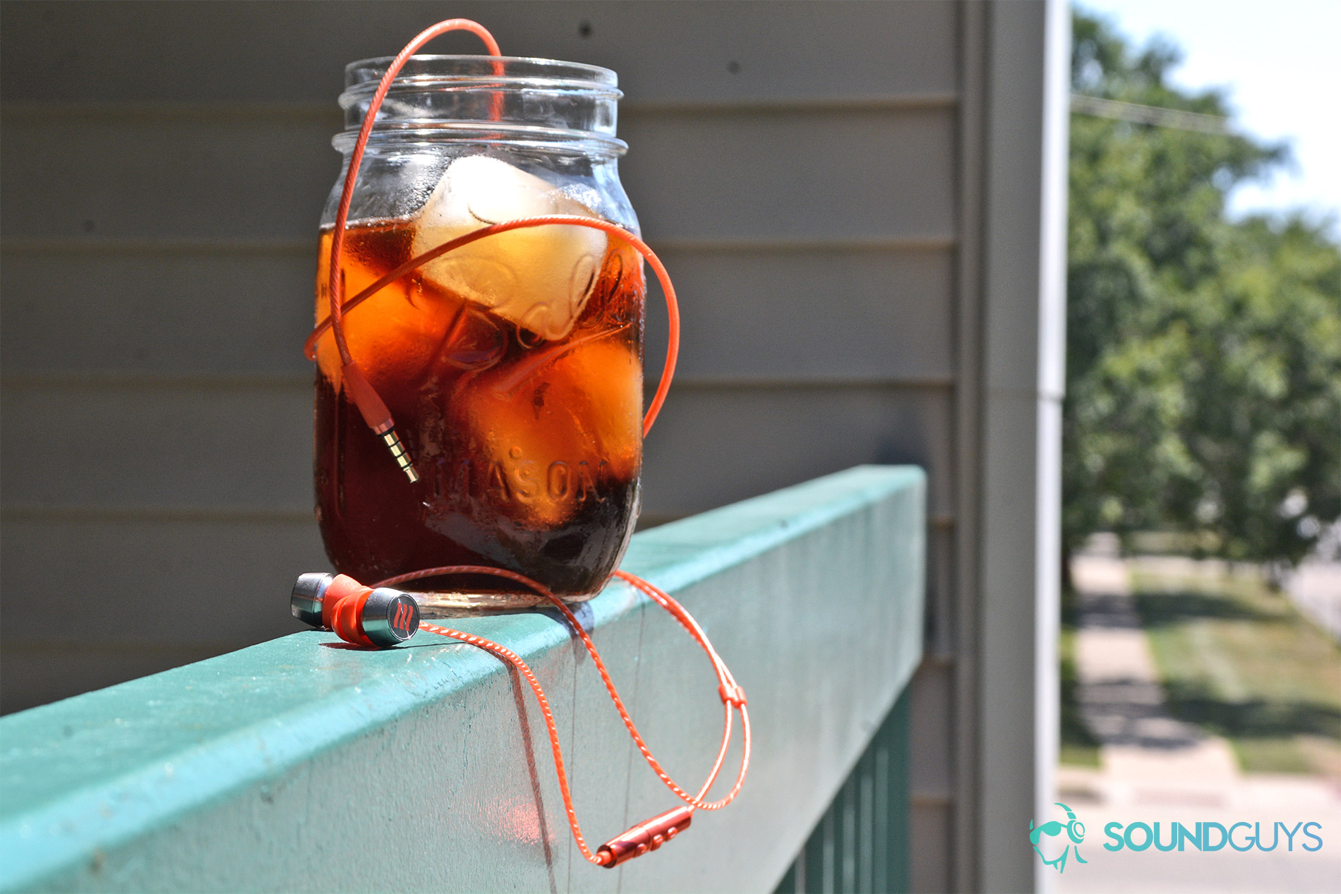 A photo of the Echobox Traveler in-ears on a railing, flaked by an iced coffee.