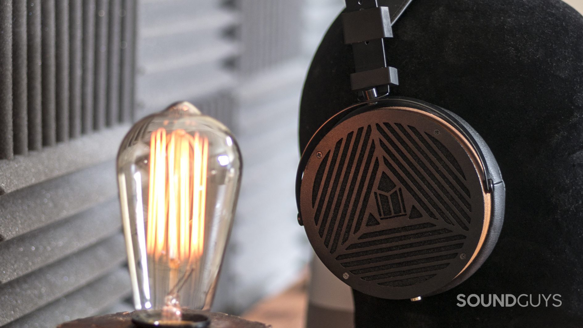 The Monoprice Monolith M1060 open-back, over-ear headphones next to lightbulb.