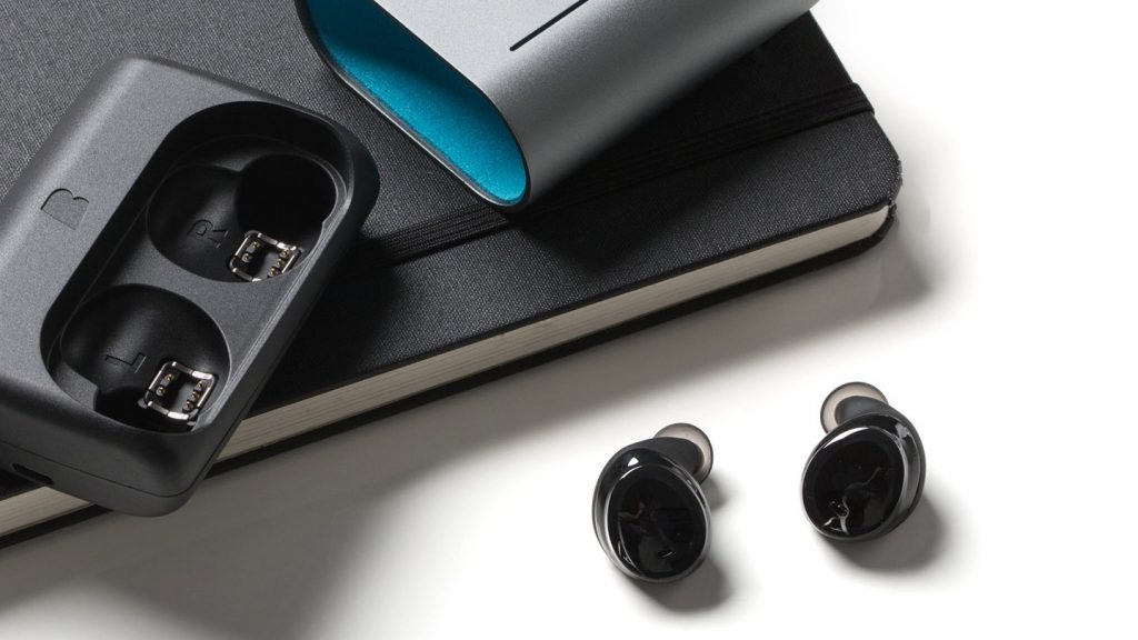 best waterproof headphones: Bragi Dash Pro on a white background near a sketchbook.