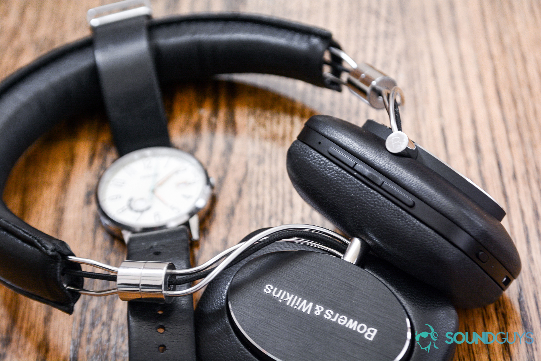 B&W_P5Wreless_3 Bowers and Wilkins P5 Wireless: The headphones with a black watch between the headband on wood surface.
