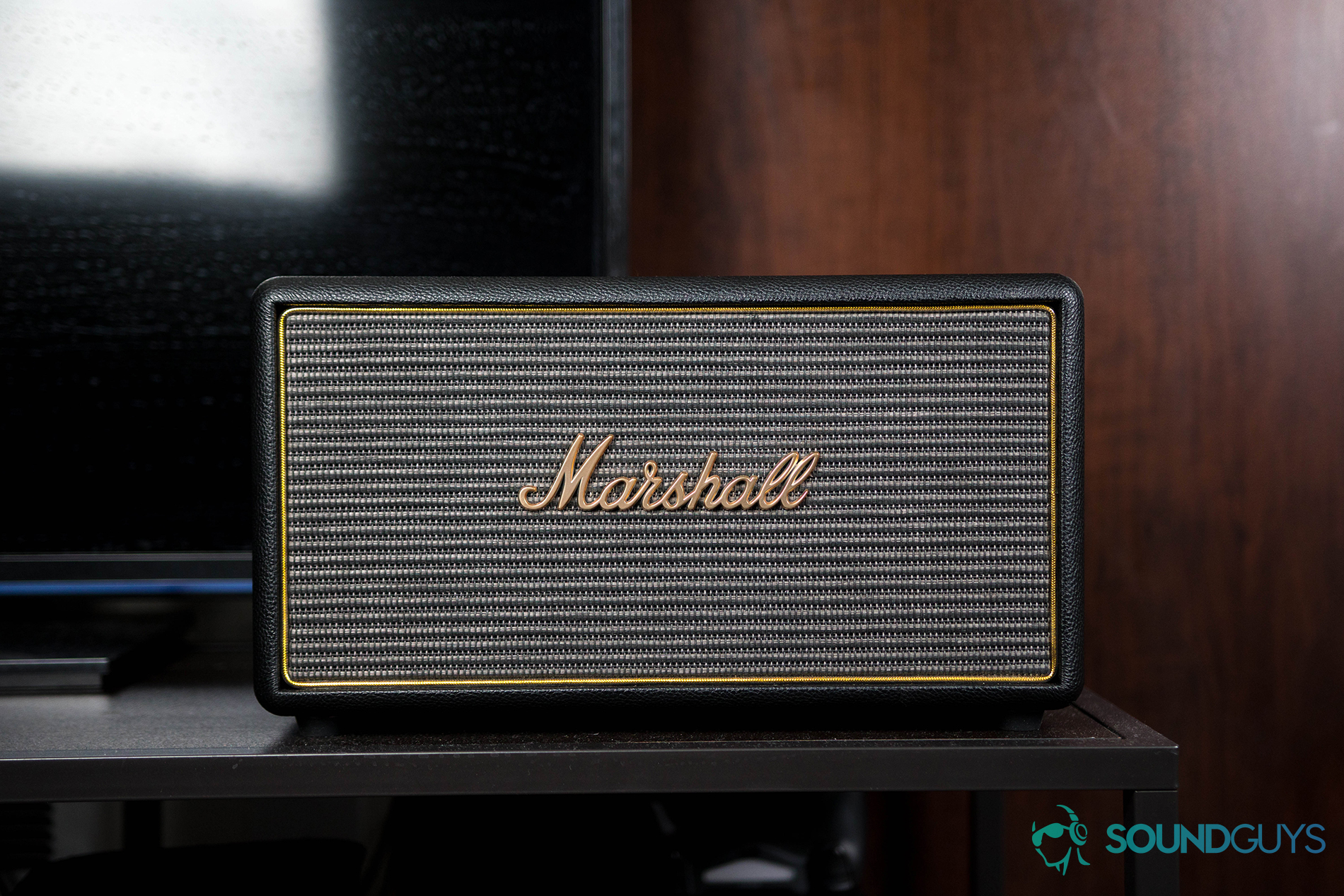 A picture of the Marshall Stanmore speaker against a dark wood wall.