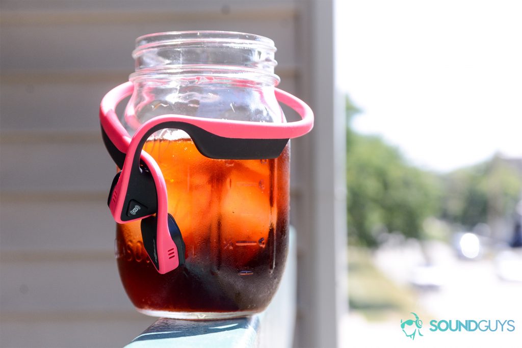 Bone conduction headphones: Aftershokz Trekz Titanium wrapped around a cold brew coffee in mason jar.