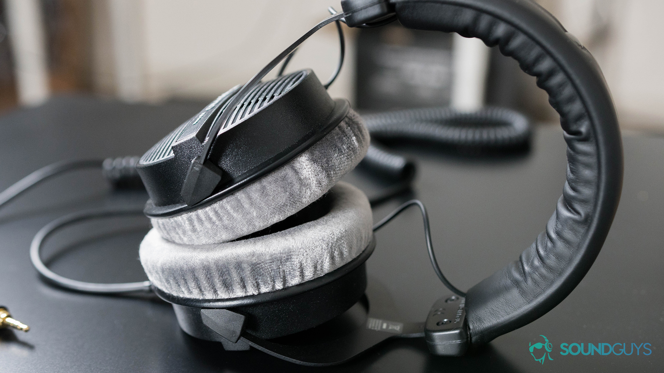 A photo of the Beyerdynamic DT 990 PRO studio headphones and their silver velour ear pads.