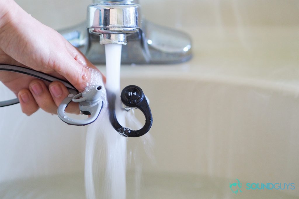 Best workout earbuds: Plantronics BackBeat FIT being held under running water.