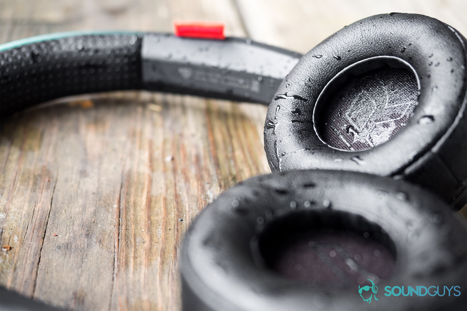 The P2i water-repellent coating isn't as good as an official IP rating, but after soaking the ear cups, the headphones held up without any issues. Pictured: The Plantronics BackBeat 500 FIT lying flat on a wood surface with water on the ear cups.