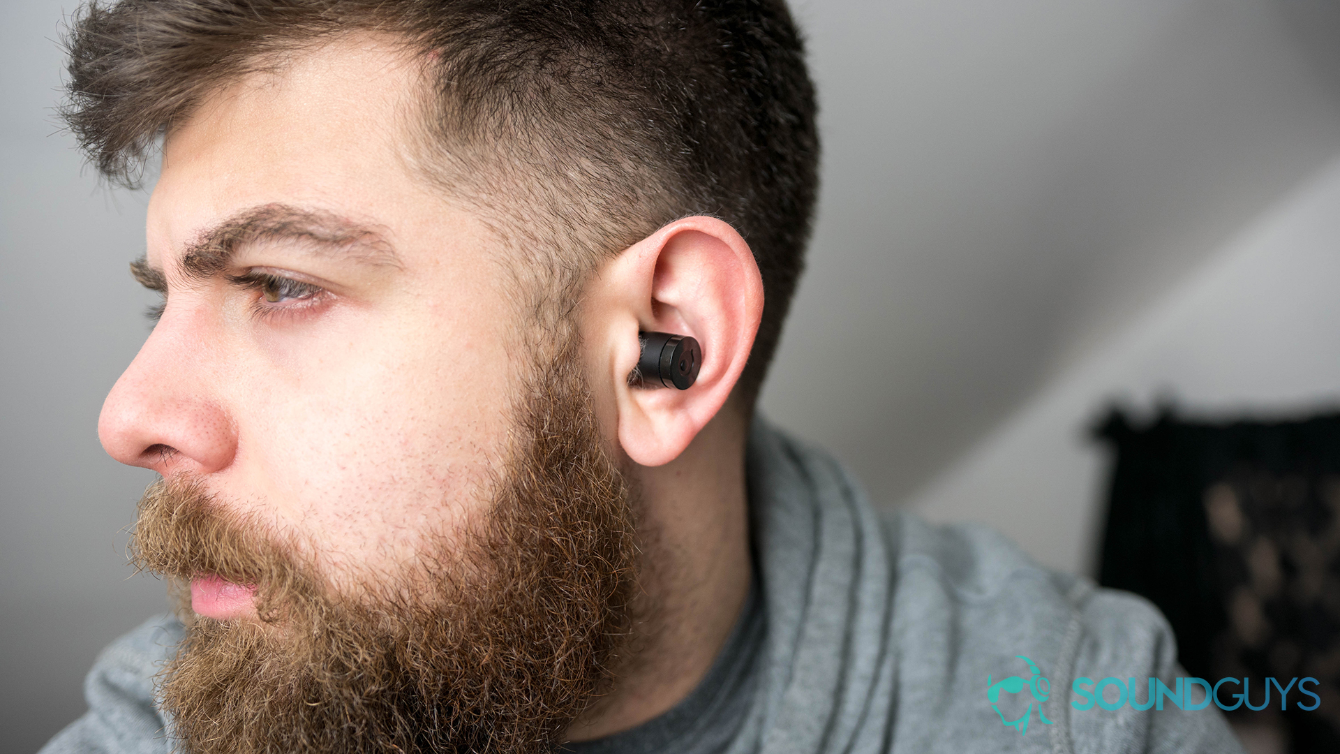 A photo of a man wearing true wireless Bluetooth earbuds.