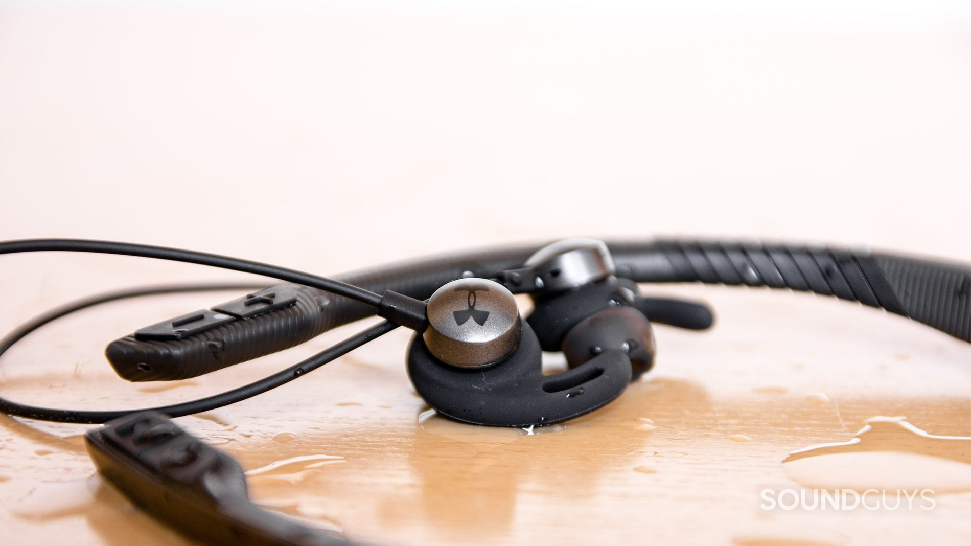 The wireless earphones have a low profile and rest comfortable in the ears. Pictured: The JBL Under Armour Sport Wireless Flex earphones with water surrounding it. The Under Armour logo is visible on the left earbud.