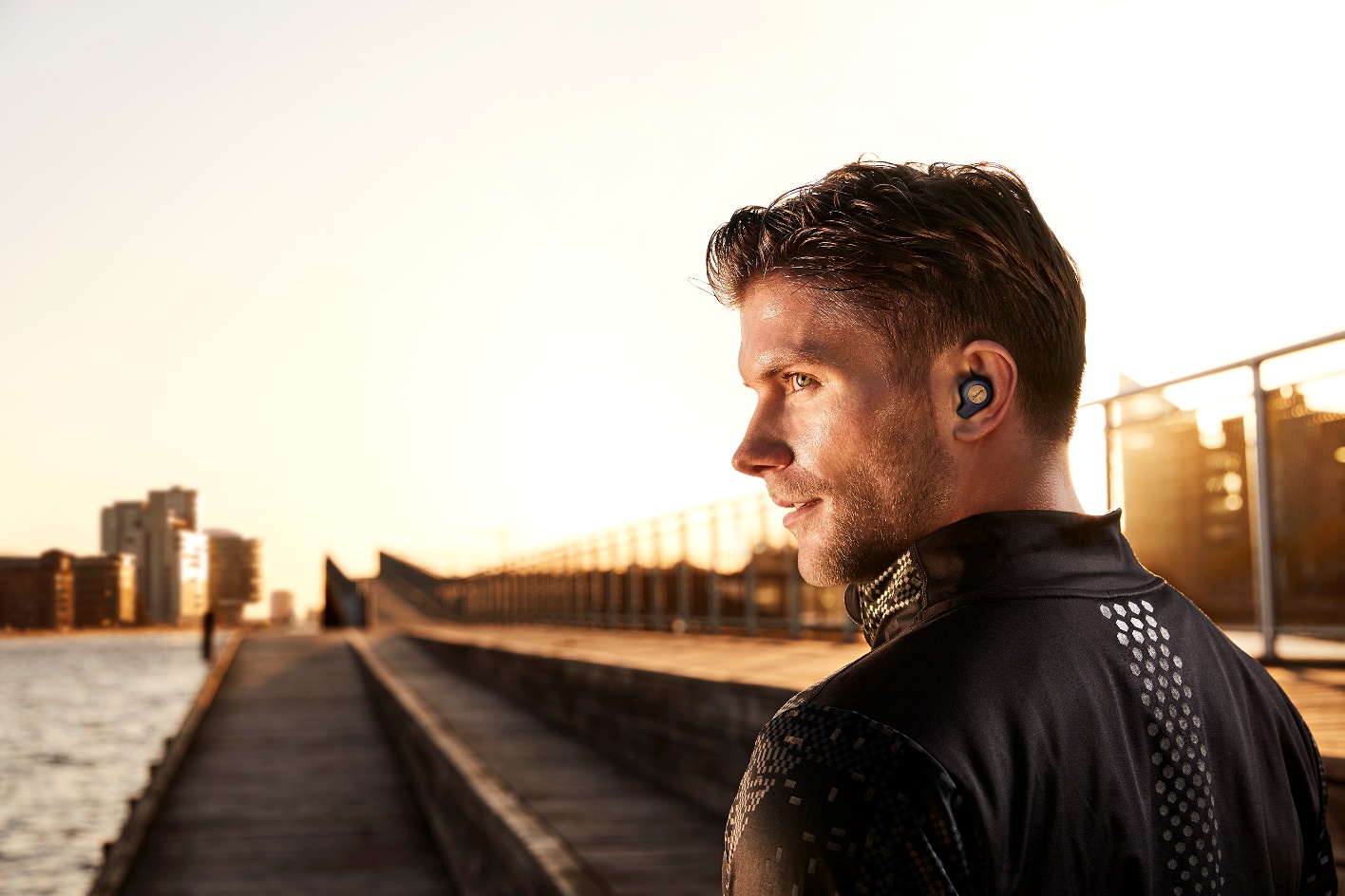 Man wearing Jabra Elite Active 65t during the sunset on a bridge.