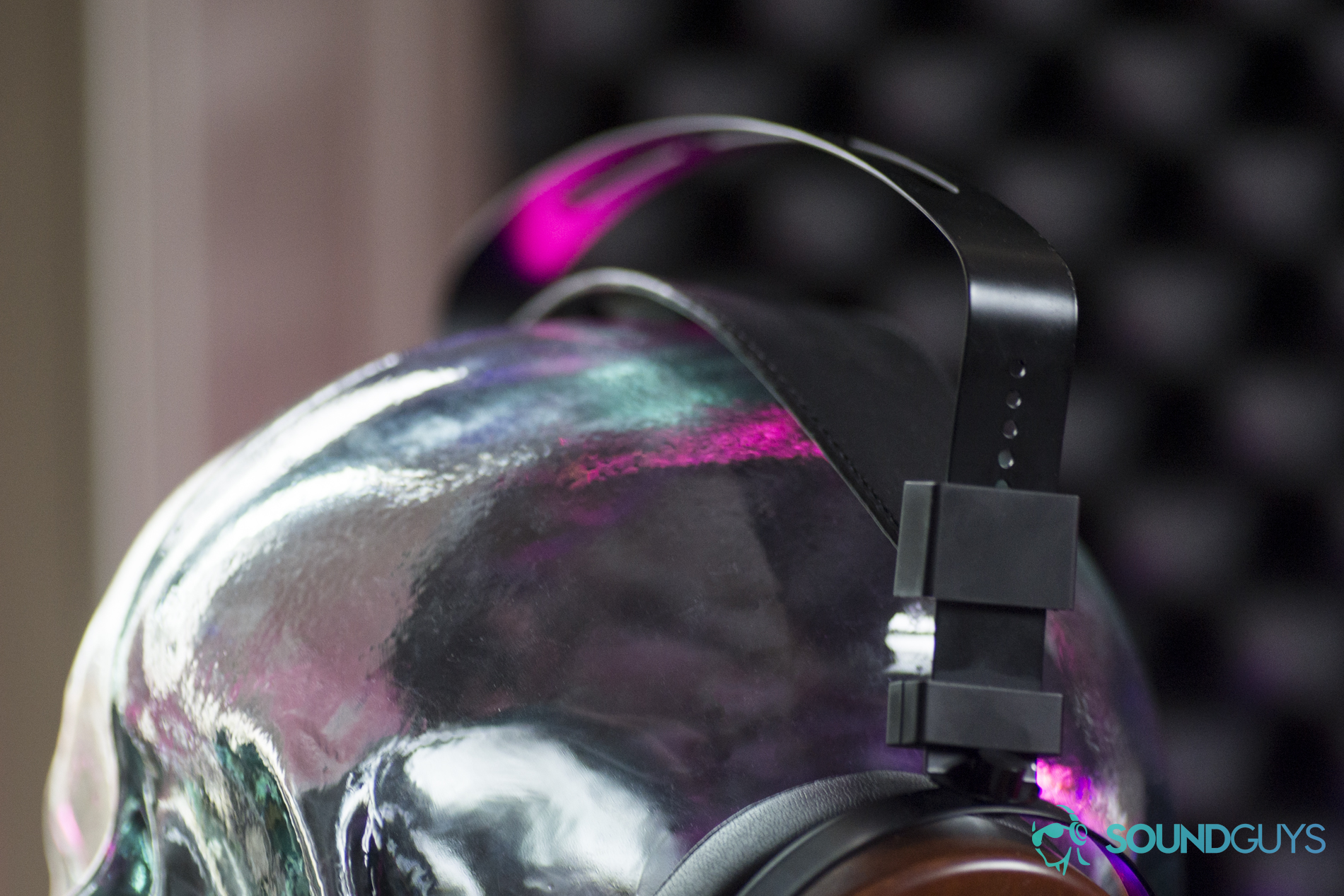 A photo of the Monoprice Monolith M565 on a glass head, showing off the band of the headphones.