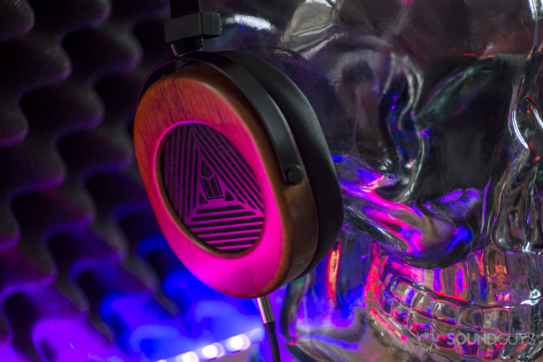 A photo of the Monoprice Monolith M565 on a glass dummy head, illuminated by colored LED light.