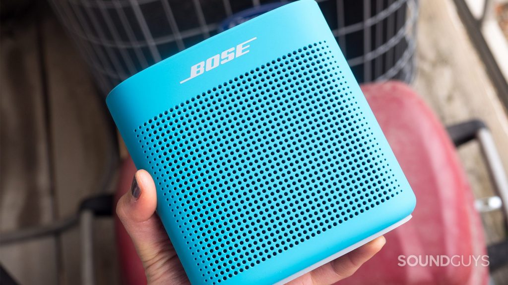 A hand holds the Bose SoundLink Color II on top of a balcony.