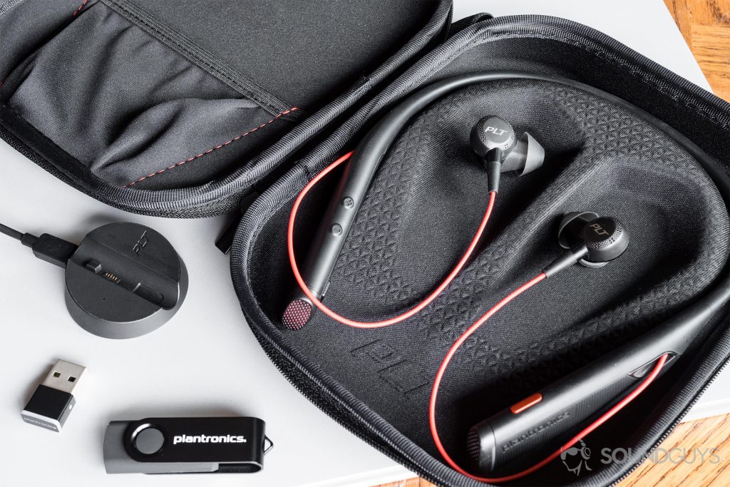 The included carrying case is the perfect combination of sturdy and flexible. Its internal pouch can easily store the included cables and cradle with room to spare. Pictured: The headset placed in the open carrying case to show off the contoured mold, which is reinforced to provide protection for the headset. On the bottom-left corner of the image is the cradle, wireless USB receiver, and a Plantronics-branded flash drive. The upper and bottom-right corners are a wood table to contrast the black product.