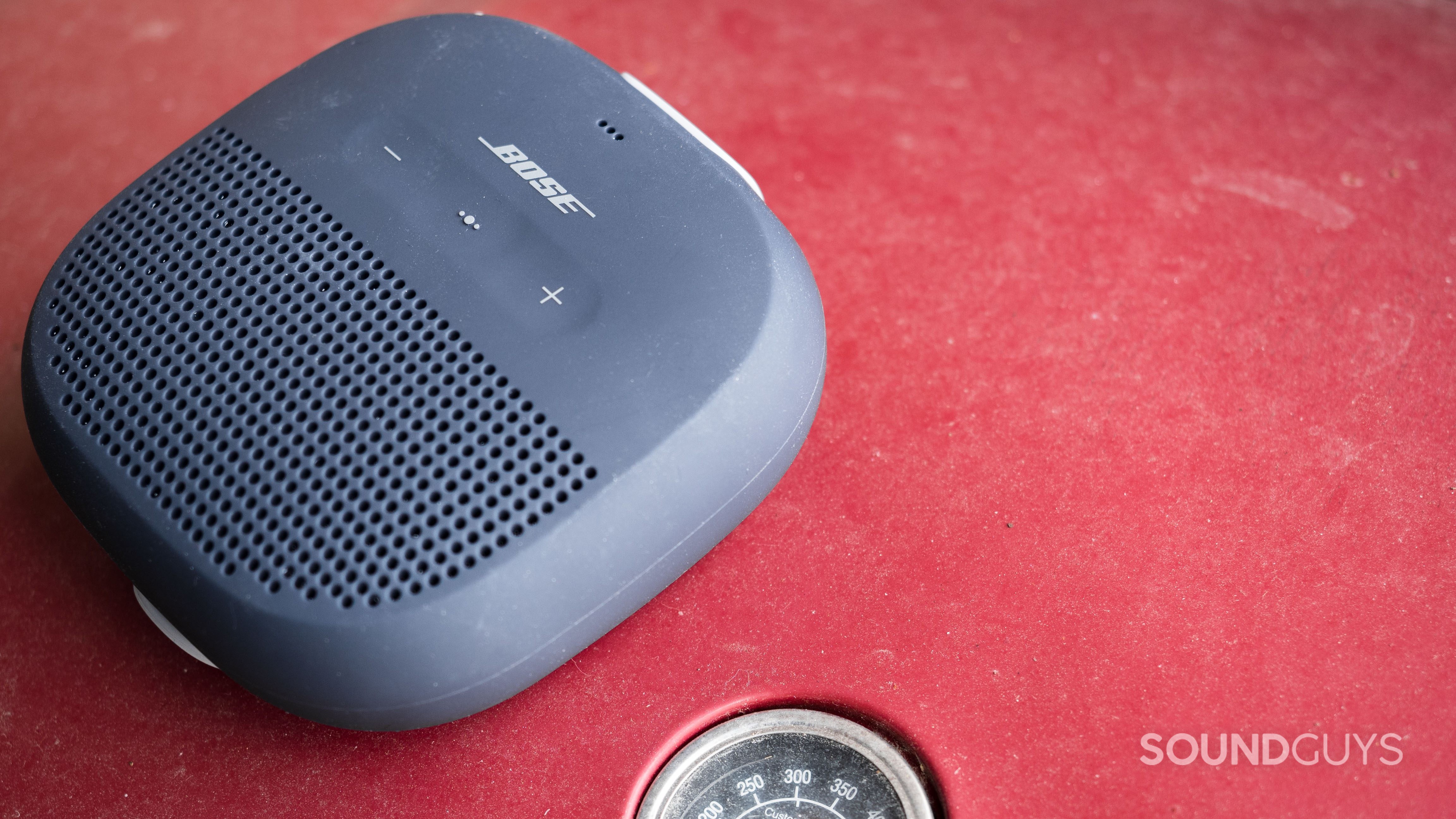 Bose SoundLink Micro on a red grill with the thermometer showing.