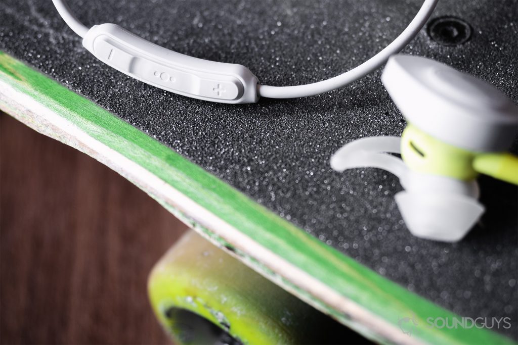 Best workout earbuds: The Bose SoundSport Wireless control module in focus with the left earbud on the bottom-right of the image. The earbuds are on a skateboard.