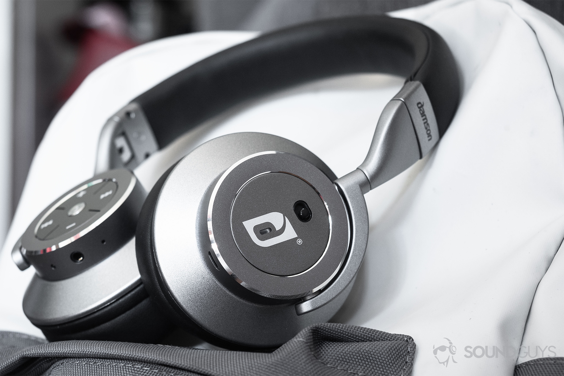 Damson HeadSpace Active Noise-Canceling review: The headphones on a white and gray backpack. The active noise-canceling toggle is facing the viewer.