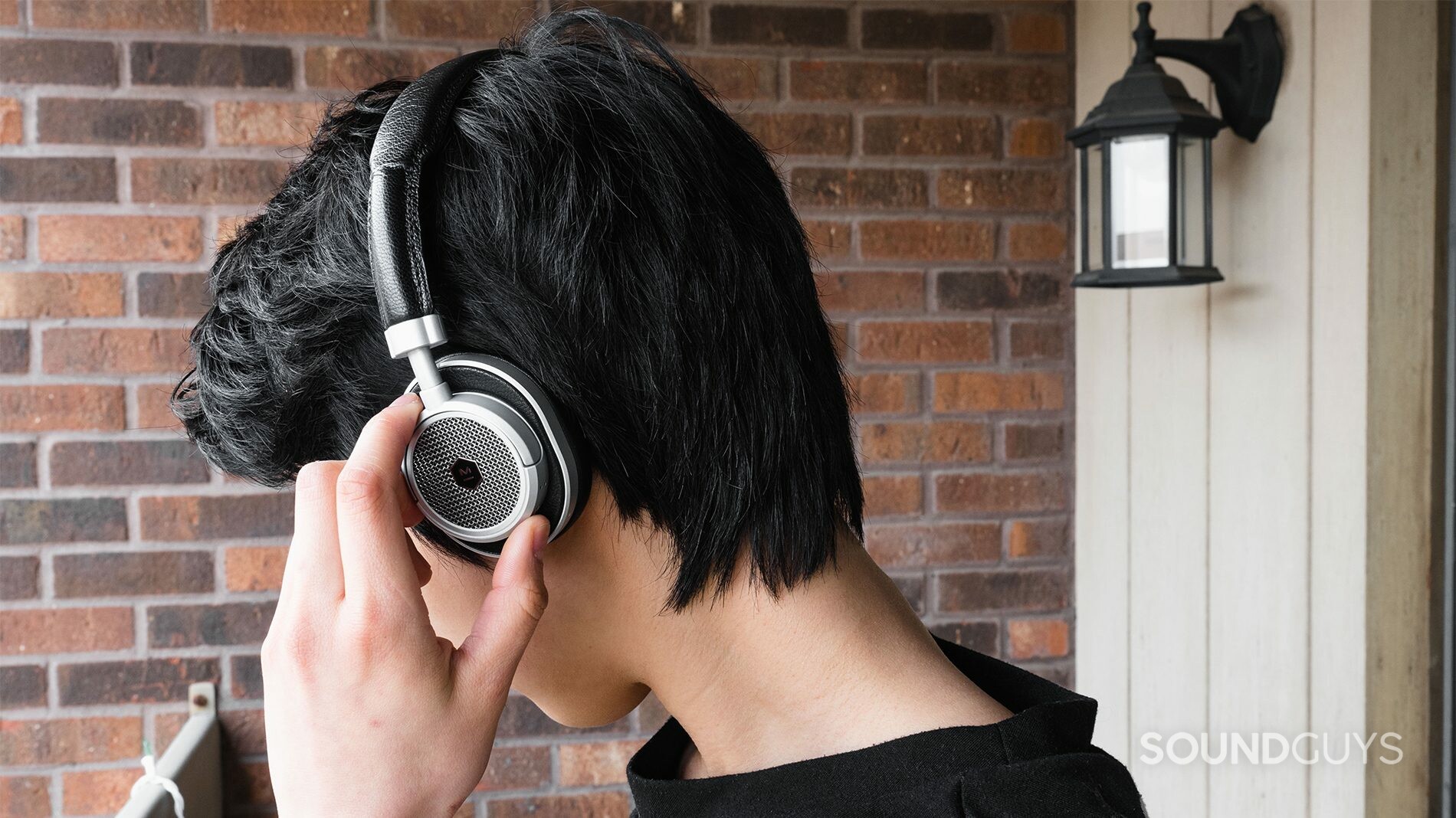 Master &amp; Dynamic MW50 review: The headphones being worn while trying to use the small playback toggles.