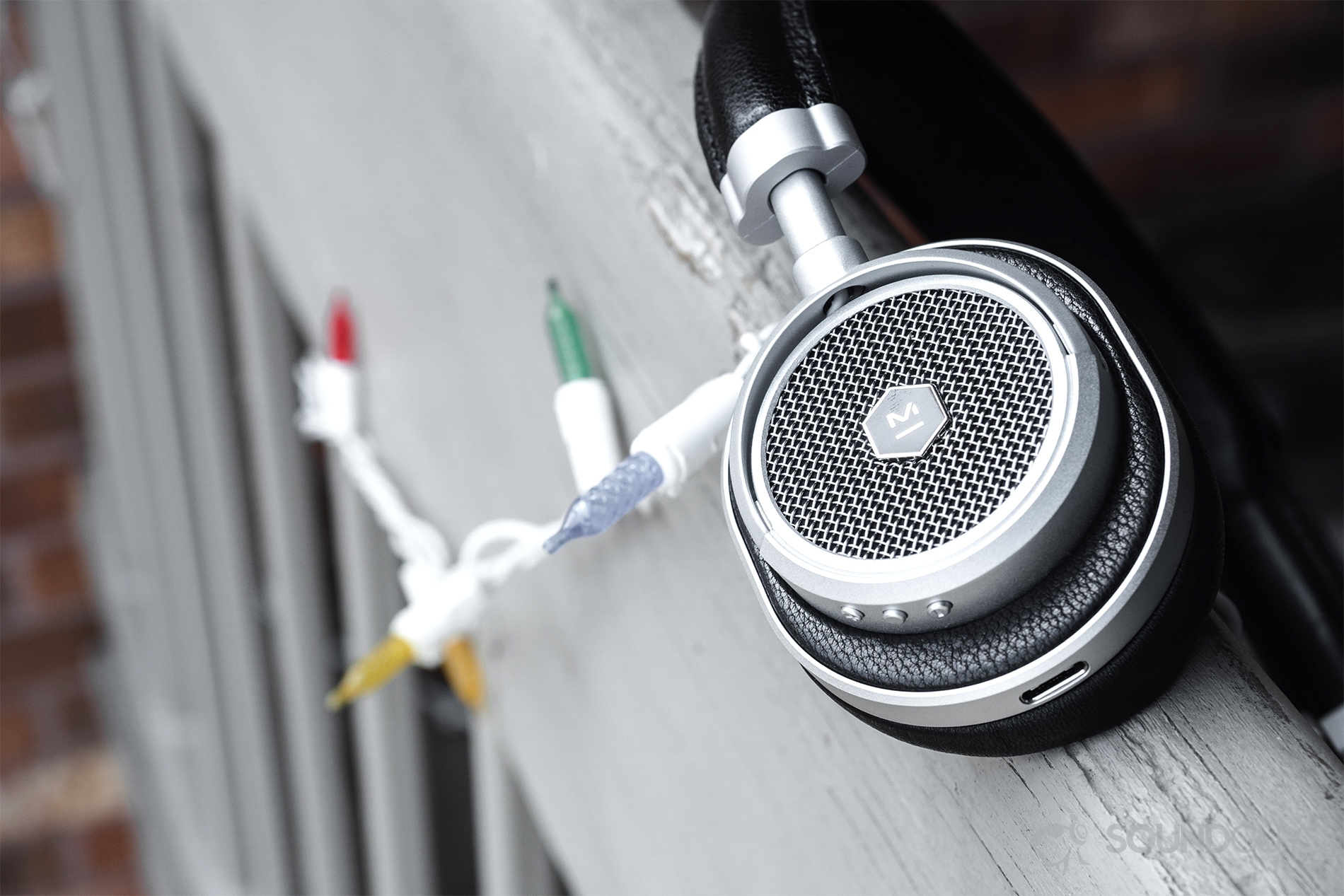 Master & Dynamic_M50 Wireless_LK_4 Master & Dynamic MW50 Wireless review: The headphones resting on a balcony railing with lights in the background.