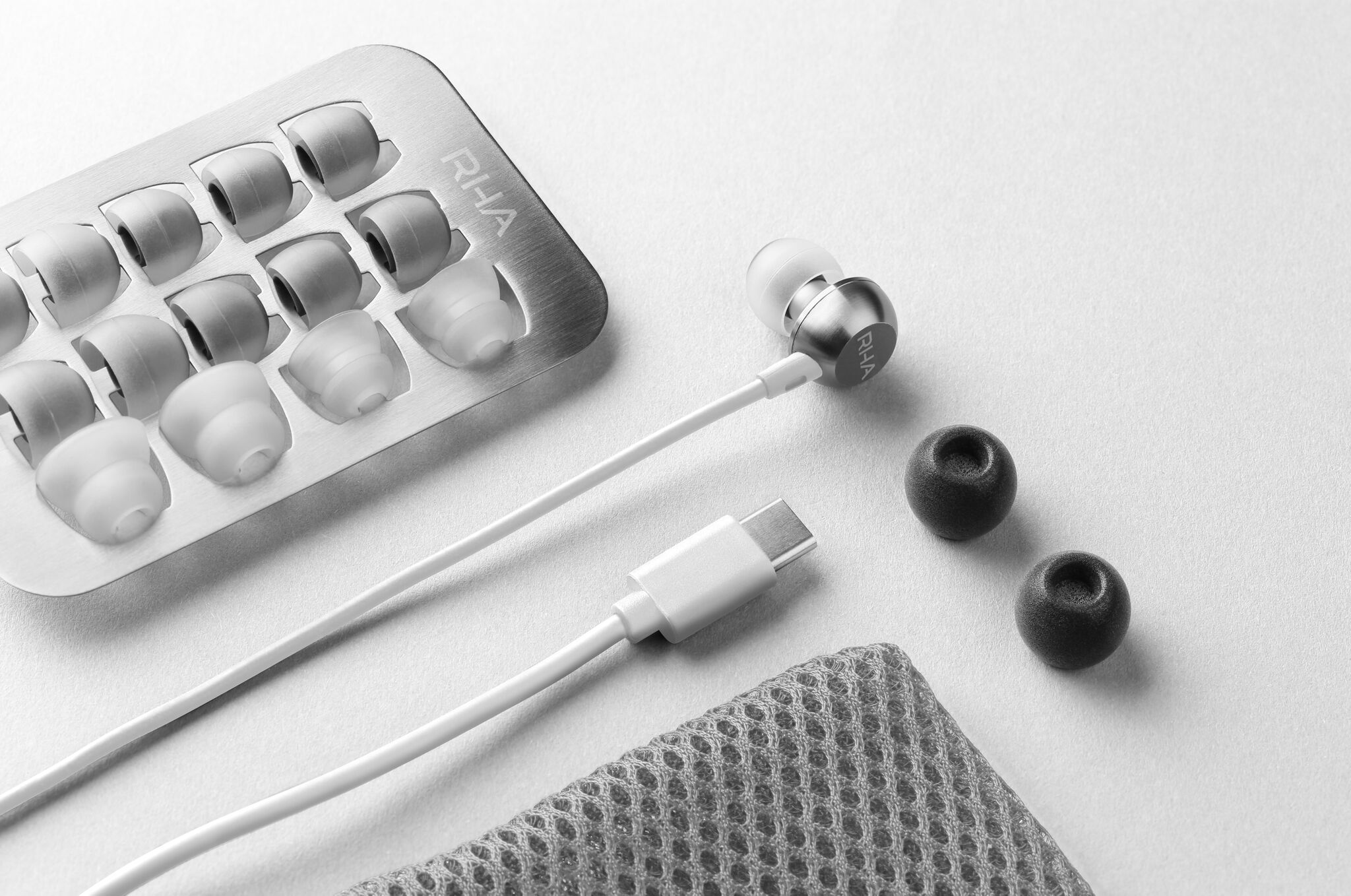 RHA MA650 Wireless in white laid out on a white surface with the accessories shown (9 pairs of ear tips, earbuds, USB-C charging cable, and a small mesh carrying pouch -- all in white)