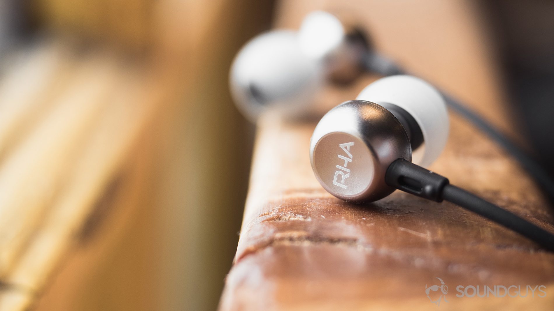 RHA MA390 review: The earbuds are placed on a railing--the closer one is facing away from the user to show off the RHA logo and other is directed toward the viewer but is slightly blurred.