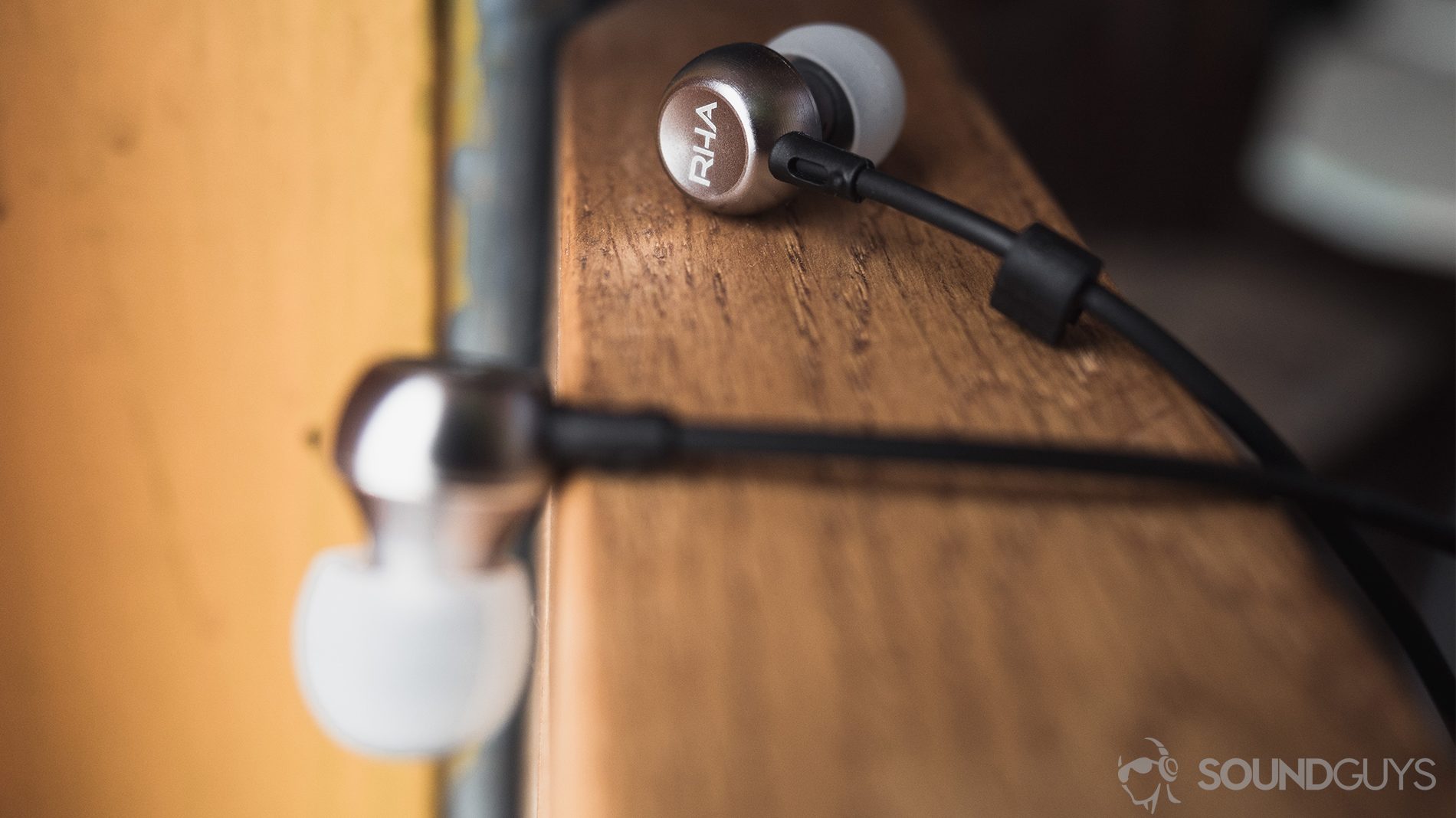 RHA MA390 review: The earbuds on a wooden railing.