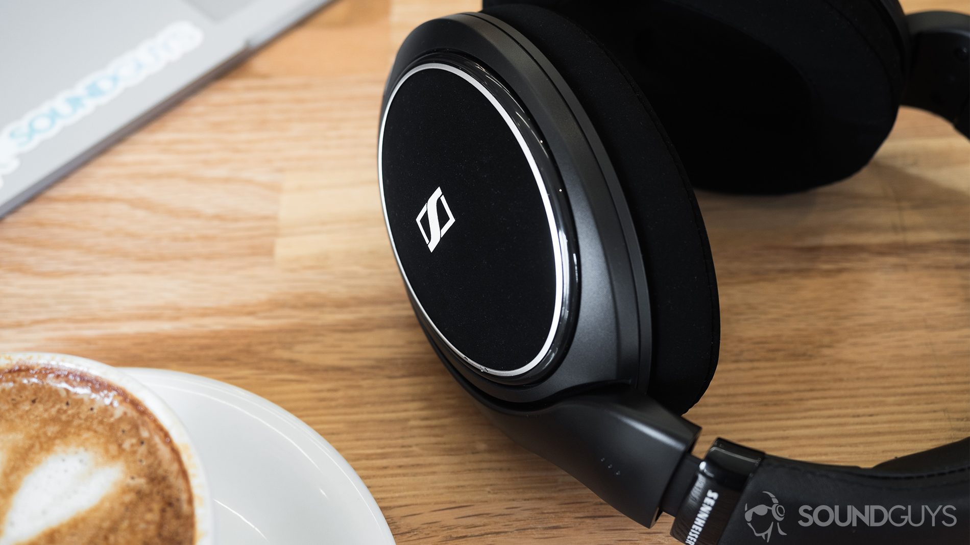 A picture of the Sennheiser HD 598 CS review: A cappucuino in the bottom-left corner of the image, the trackpad portion of a Microsoft Surface Book in the top-left corner, and the headphones taking up the right section of the image.
