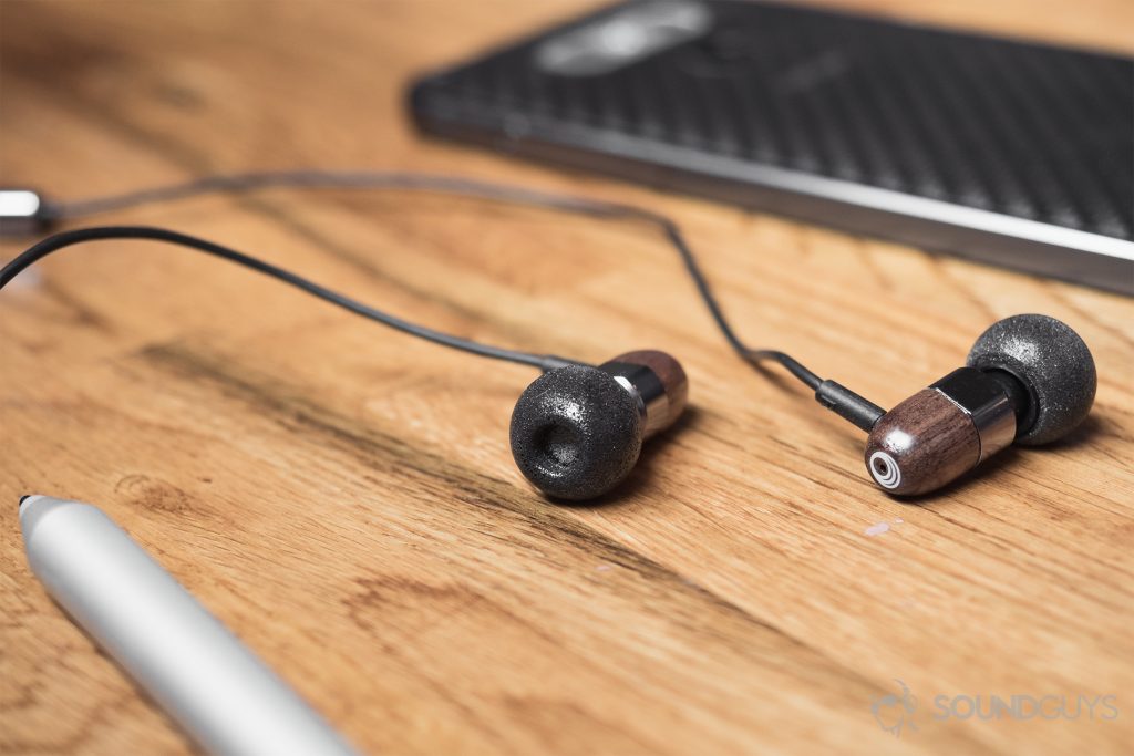 Thinksound ts03+mic review: The earbuds on a light-colored wood surface surrounded by an LG G6 in the background and a Surface pen in the foreground.