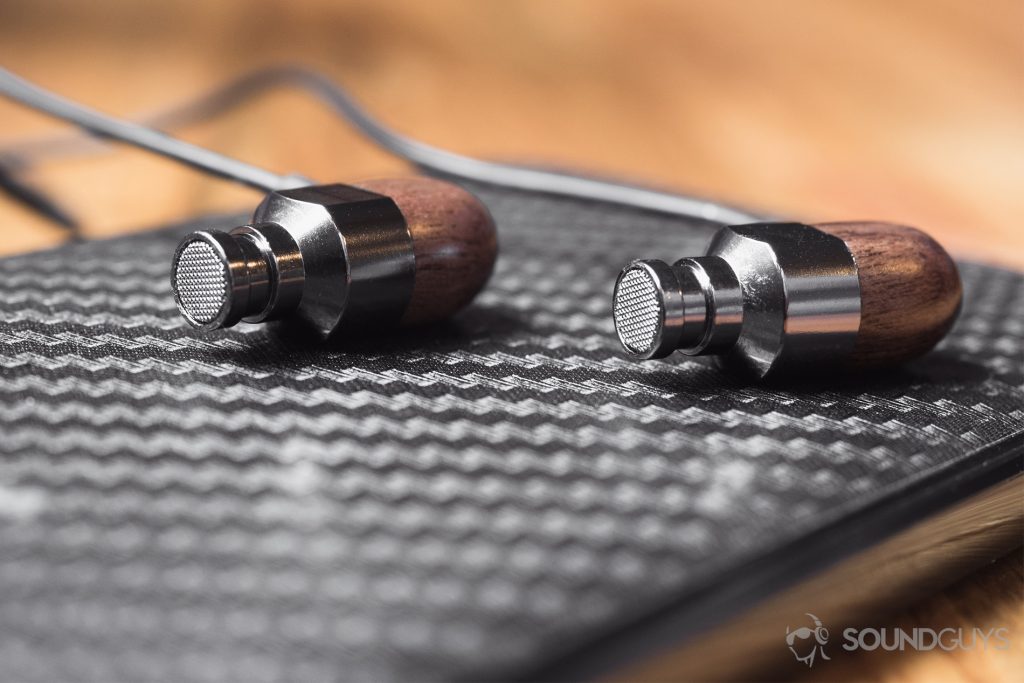 best running headphones - the earbuds on a light-colored wood surface surrounded by an LG G6 in the background.