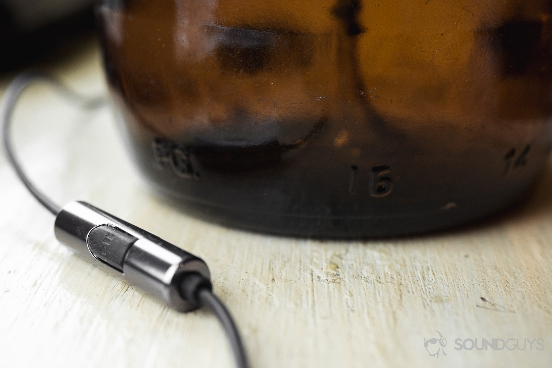 Thinksound ts03+mic review: A close-up of the mic/remote in front of a dark brown glass bottle.