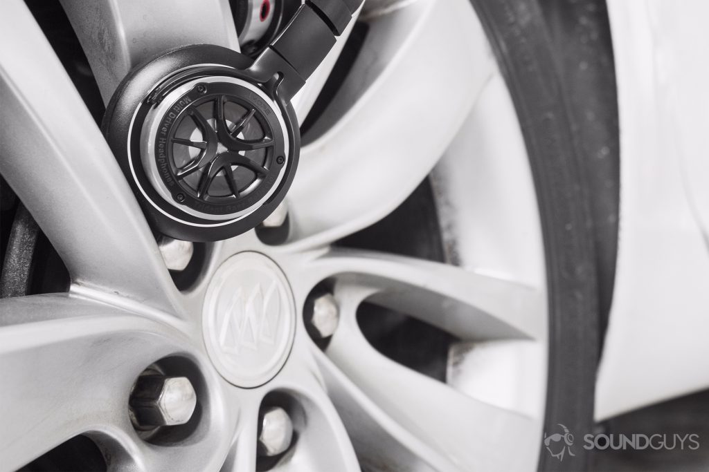 1More Triple-Driver Over-Ear review: The headphones lodged in a car tire to show the similar design.