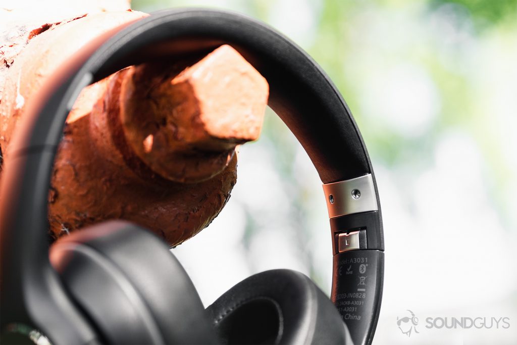Anker Soundcore Vortex review: A close-up of hte headphones hanging from an orange fire hydrant with the focus on the metal hinges.