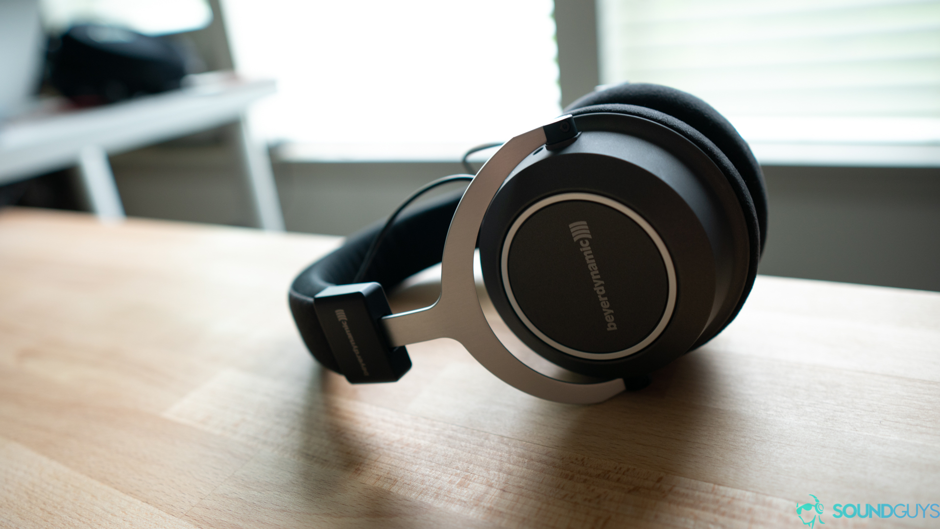 Image shows the Beyerdynamic Amiron Wireless resting on its side on a wood table.
