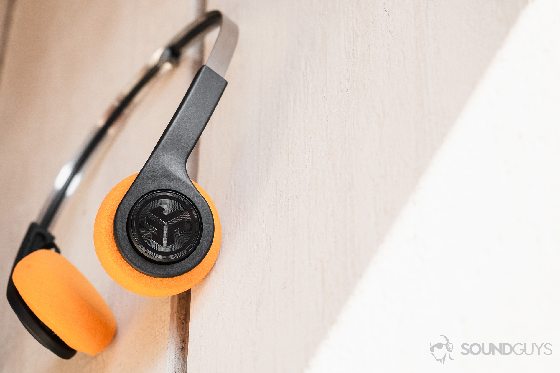 JLab Rewind Wireless Retro: The headphones resting atop a nail on a wood-paneled wall.