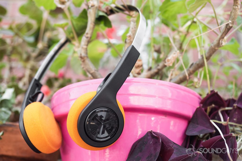 JLab Rewind Wireless Retro: The headphones are in a potted plant, hanging from the stems. The pot is a saturated pink.