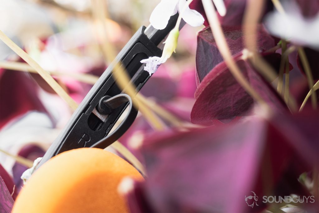 JLab Rewind Wireless Retro: A close-up of the flat-ribbon cable on the headband interior. The headphones are in a bed of purple flowers.