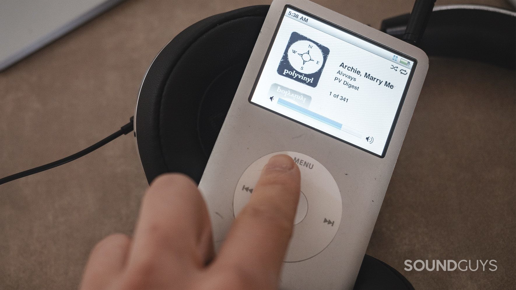  A finger turning up the volume on an iPod Classic (silver).